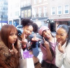 four girls are posing for the camera with their fingers in the air