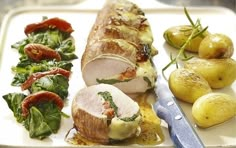 a white plate topped with meat and veggies next to a knife on top of a cutting board