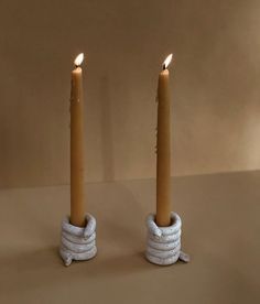 two candles with rope wrapped around them sitting next to each other on a brown surface