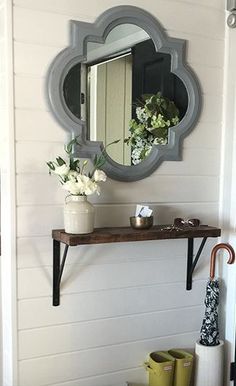 a mirror hanging on the side of a wall next to a potted plant and umbrella