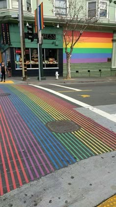 a rainbow painted street with people walking on the sidewalk