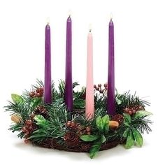 purple candles are arranged in a basket with greenery and berries