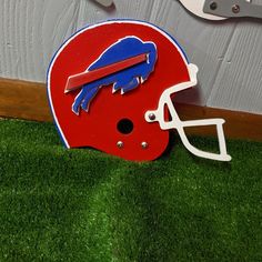 a football helmet with a buffalo logo on it sitting in the grass next to a wall