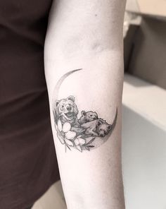 a woman's arm with a bear and moon tattoo on the left upper arm