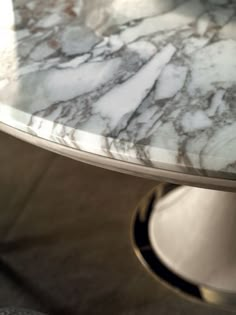 a marble top table with silver base and metal legs, in a living room setting