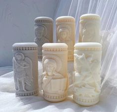 five different colored vases sitting next to each other on a white cloth covered surface