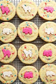 many cookies with pink and white frosting are arranged on a cooling rack