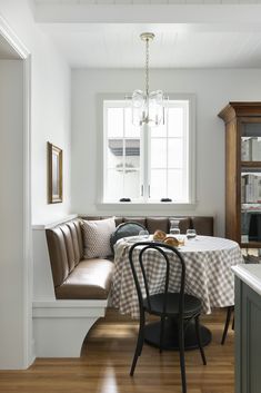 a dining room with a table, bench and window in the corner next to it