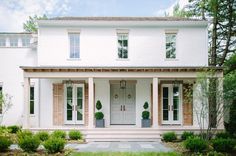 a large white house with two story windows and shutters on the front door is surrounded by greenery