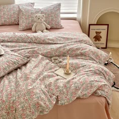 a teddy bear sitting on top of a bed next to pillows and a pillow case