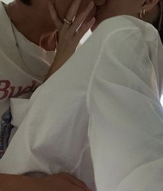 the woman is kissing the man's face with both hands on his chest and wearing a white shirt