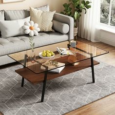 a living room with a couch, coffee table and potted plant in the corner