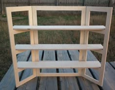 a wooden shelf sitting on top of a wooden floor next to a fence and grass