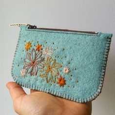 a hand holding a small blue purse with flowers on it