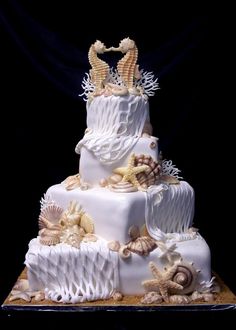 a three tiered wedding cake with sea shells and starfish on the bottom layer