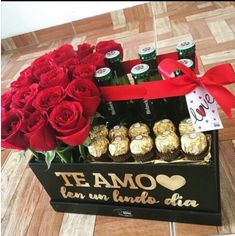 a box filled with roses and chocolates on top of a wooden floor next to bottles of beer