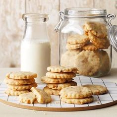 cookies and milk are sitting on a cooling rack next to a glass jar full of milk