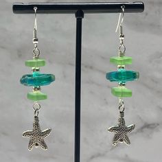 Handcrafted By Blue Moon Jewelry This Beautiful Pair Of Handcrafted Earrings Is Calling You To The Beach. Teal Blue And Green Sea Glass Wire Wrapped With Starfish Charms. Sterling Silver Ear Wires. Will Come In An Organza Jewelry Bag Ocean-inspired Green Jewelry For Vacation, Green Ocean-inspired Jewelry For Vacation, Adjustable Green Starfish Jewelry, Handmade Green Starfish Jewelry, Handmade Green Starfish-shaped Jewelry, Nickel-free Blue Earrings For Vacation, Green Dangle Jewelry For The Beach, Green Ocean-inspired Nickel-free Jewelry, Adjustable Green Jewelry With Starfish Charm