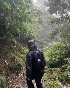 a man with a backpack walking up a trail in the woods