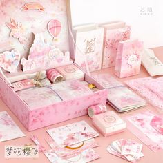 a pink box filled with lots of cards and paper decorations on top of a table