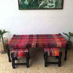 a colorful bench and footstool in front of a painting