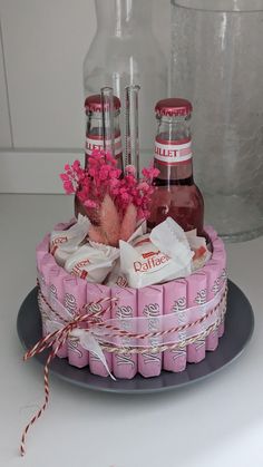 a cake made to look like it is decorated with liquor bottles and pink flowers on top