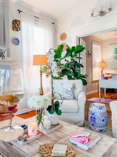 a living room filled with furniture and flowers on top of a coffee table next to a glass of wine