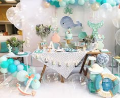 an ocean themed party with balloons, cake and desserts on the table for children's birthday