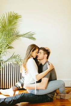 a man and woman sitting next to each other in front of a radiator