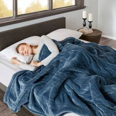 a woman laying in bed under a blue blanket