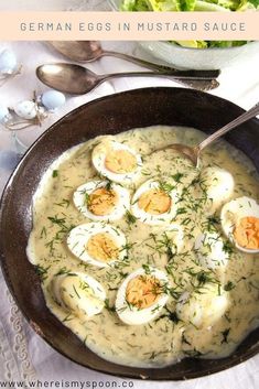 a bowl filled with soup and eggs on top of a table next to a salad