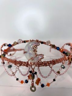 Our Lunar Serenity Crown was handcrafted with pure and rose copper wire, the intricate details highlight a stunning opalite crescent moon at its center. Boulder and fire opal beads glisten, while an array of glass and Preciosa beads add a touch of ethereal sparkle. Delicate stainless steel rose chains drape along the base, creating a balance in this work of art. Wear it to feel connected to the universe and the inner power that lies within you. Opalite may be a man-made glass that mimics the eth Connected To The Universe, Inner Power, Opal Beads, Crescent Moon, Intricate Details, Fire Opal, Copper Wire, Crystal Jewelry, The Universe