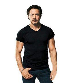 a man in black shirt and jeans standing next to a white wall with the words robert downey on it