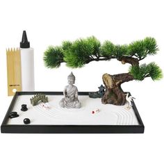 a bonsai tree and buddha statue on a tray with other items in front of it