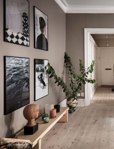 a long hallway with pictures on the wall and plants in vases next to it