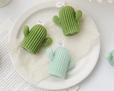 three small green cactus decorations on a white plate