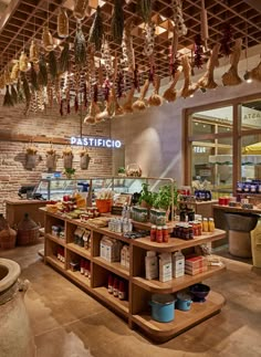 the inside of a restaurant with lots of food hanging from the ceiling and wooden shelves