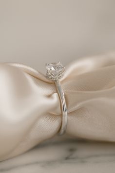 a diamond ring on top of a white satin bow