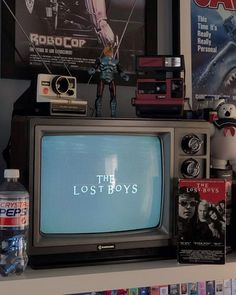 an old tv sitting on top of a shelf in front of posters and other items