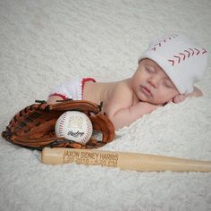 a baby laying next to a baseball bat and glove on a white blanket with the name aaron sidney harris written on it