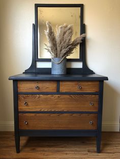 a dresser with a mirror and some dried plants on it