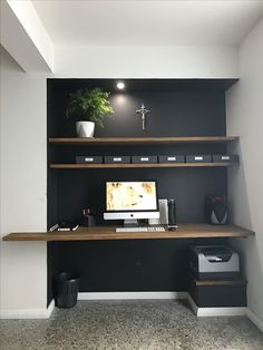 a desk with a computer on top of it in front of a wall mounted monitor