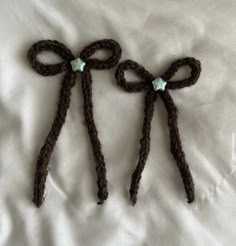 two brown crocheted bows with crystal stones on them sitting on a white sheet