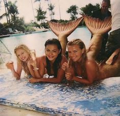 three beautiful young women laying on top of a swimming pool next to eachother