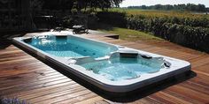 a hot tub sitting on top of a wooden deck next to a lush green field