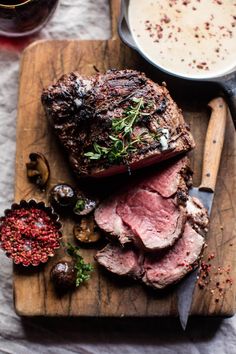 a steak on a cutting board next to some sauces