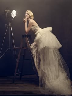 a woman in a white dress sitting on a chair next to a camera and light