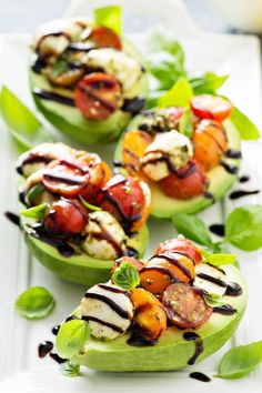 four stuffed avocados with grilled vegetables and sauces on them are sitting on a white plate