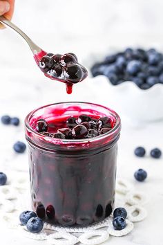 a spoon full of blueberry jam with berries around it