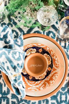 an orange and blue table setting with dishes, napkins and silverware on it